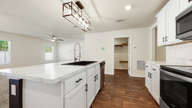 kitchen with sink, a textured ceiling, a kitchen island with sink, white cabinets, and appliances with stainless steel finishes