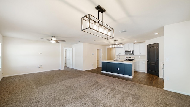 kitchen with white cabinets, decorative light fixtures, a kitchen island with sink, and appliances with stainless steel finishes