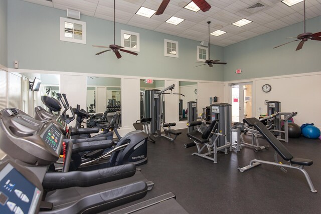 gym with ceiling fan, a paneled ceiling, and a high ceiling