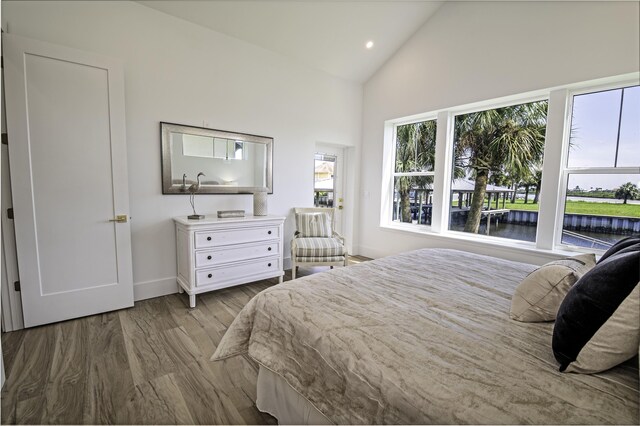 bedroom featuring a water view, high vaulted ceiling, and light hardwood / wood-style flooring