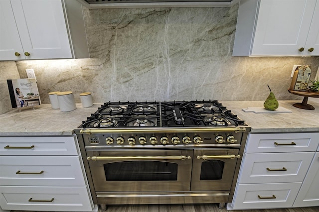 kitchen featuring white cabinets, range with two ovens, and light stone counters