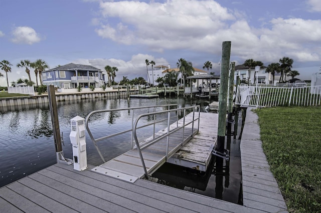 view of dock featuring a lawn and a water view