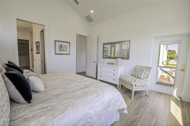 bedroom with light wood-type flooring, a spacious closet, high vaulted ceiling, and a closet