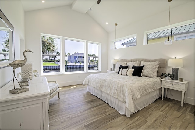 bedroom with beam ceiling, multiple windows, hardwood / wood-style floors, and high vaulted ceiling