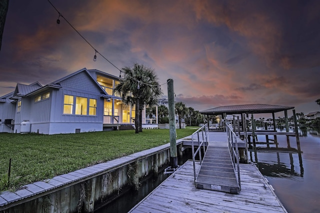 view of dock with a yard and a water view