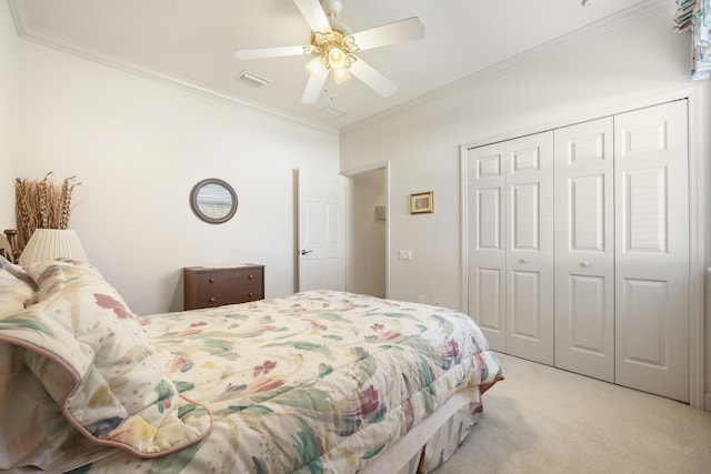 carpeted bedroom with ceiling fan, ornamental molding, and a closet