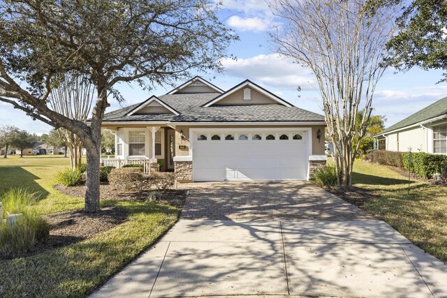 view of front of house with covered porch, a garage, and a front yard