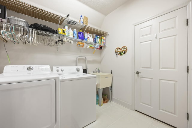 washroom with washing machine and dryer, light tile patterned floors, and a textured ceiling