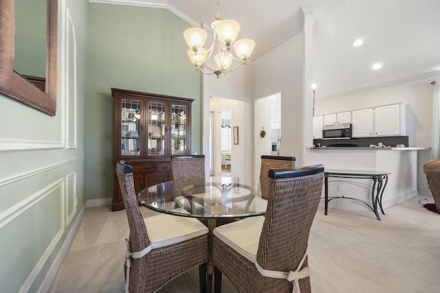 carpeted dining room featuring a towering ceiling, a chandelier, and ornamental molding