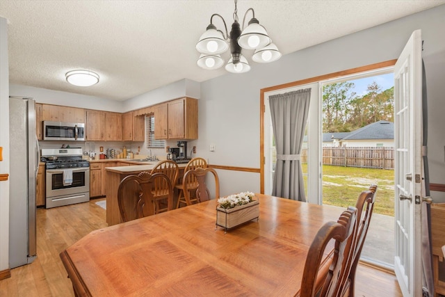 dining space featuring a chandelier, sink, light hardwood / wood-style flooring, and a textured ceiling