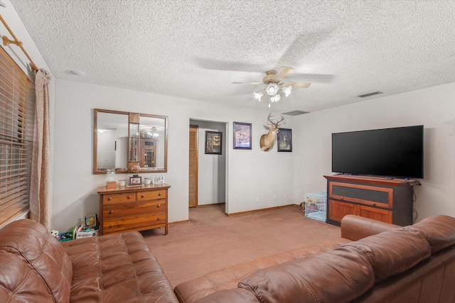 living room featuring ceiling fan, light colored carpet, and a textured ceiling