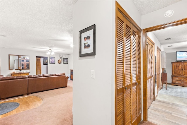 corridor featuring light colored carpet and a textured ceiling