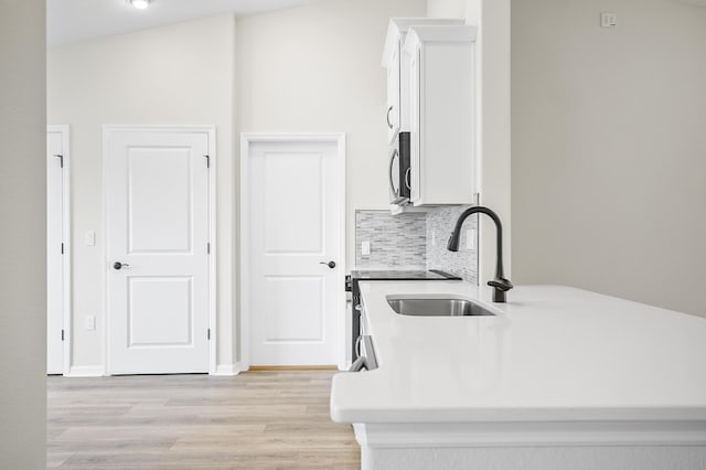 kitchen featuring white cabinetry, sink, decorative backsplash, and light hardwood / wood-style floors