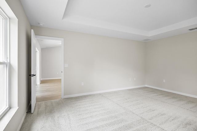 carpeted spare room featuring a raised ceiling