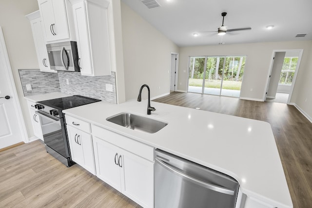 kitchen featuring sink, appliances with stainless steel finishes, white cabinetry, backsplash, and light hardwood / wood-style floors