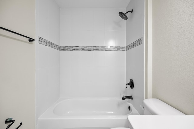 bathroom with tiled shower / bath combo and toilet