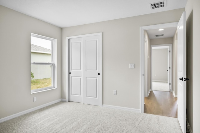 unfurnished bedroom with light colored carpet and a closet