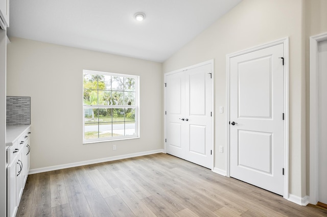 unfurnished bedroom featuring lofted ceiling, light hardwood / wood-style floors, and a closet