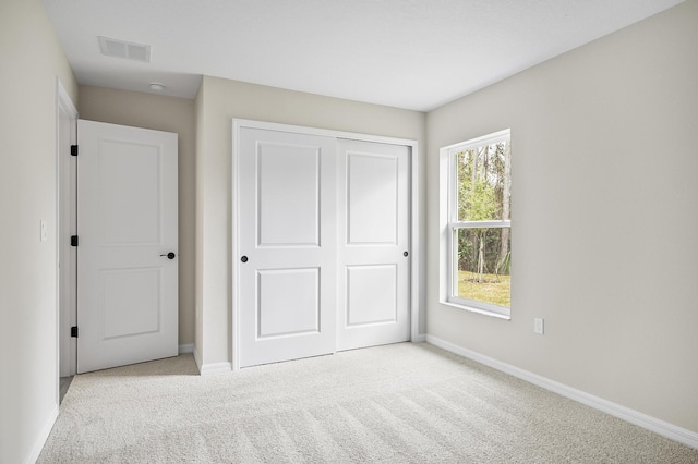 unfurnished bedroom with light colored carpet and a closet