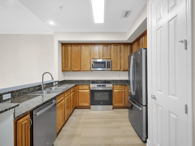 150 Pantano Cay Blvd Unit 2303, Saint Augustine, FL 32080 - kitchen with stainless steel appliances, a sink, dark stone counters, light wood finished floors, and brown cabinets