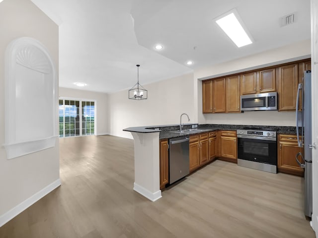 150 Pantano Cay Blvd Unit 2303, Saint Augustine, FL 32080 - kitchen with stainless steel appliances, a sink, light wood finished floors, a peninsula, and brown cabinetry