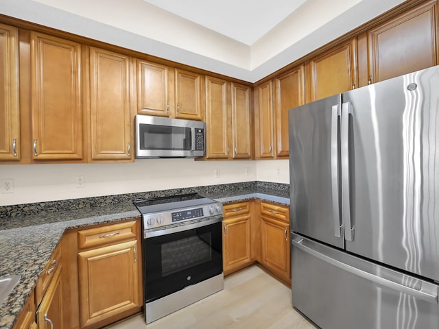 150 Pantano Cay Blvd Unit 2303, Saint Augustine, FL 32080 - kitchen featuring appliances with stainless steel finishes, brown cabinetry, dark stone counters, and light wood-style floors
