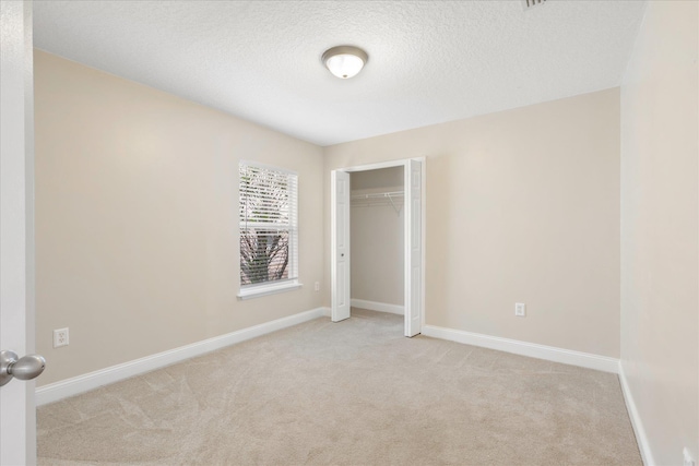 unfurnished bedroom with light colored carpet, a textured ceiling, and a closet