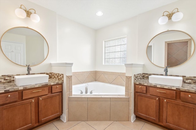 bathroom with tiled tub, vanity, and tile patterned flooring