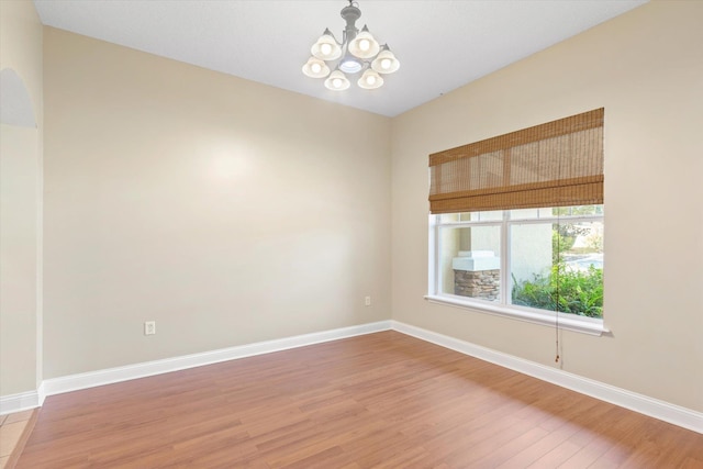 empty room with hardwood / wood-style flooring and a chandelier