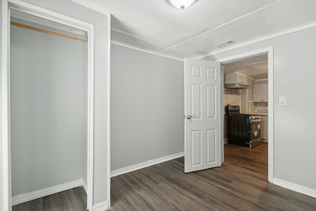 unfurnished bedroom with dark hardwood / wood-style flooring, crown molding, and a closet