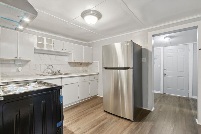 kitchen with light hardwood / wood-style floors, stove, white cabinetry, and stainless steel refrigerator