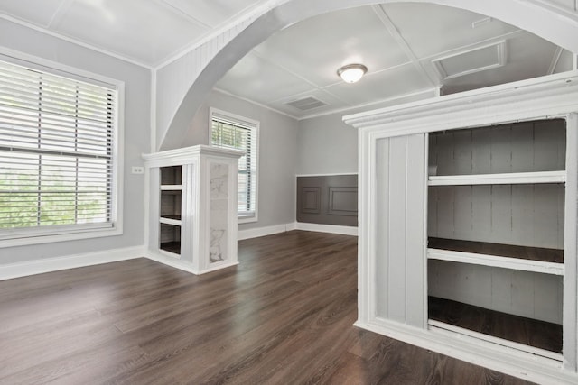 unfurnished living room with a wealth of natural light, dark hardwood / wood-style floors, and ornamental molding