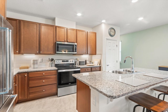 kitchen with appliances with stainless steel finishes, a breakfast bar, and an island with sink