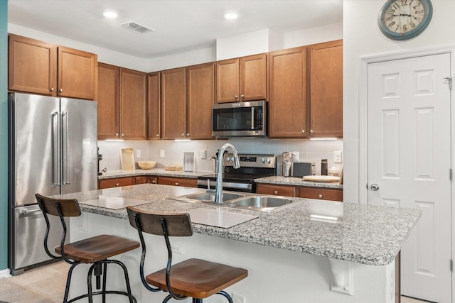 kitchen with sink, a breakfast bar area, an island with sink, and appliances with stainless steel finishes