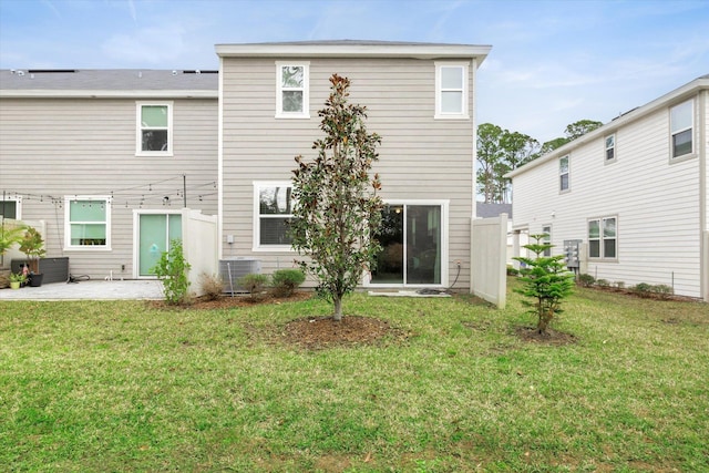 rear view of property with cooling unit, a patio area, and a lawn