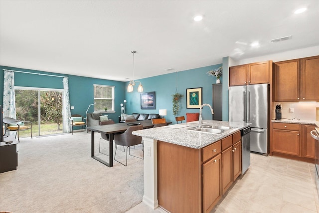 kitchen with pendant lighting, sink, light stone counters, stainless steel appliances, and light carpet