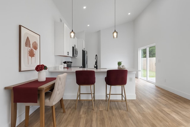 461 S Woodlawn St, Saint Augustine, FL 32084 - kitchen featuring light countertops, stainless steel appliances, a peninsula, light wood finished floors, and white cabinets