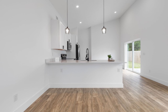 461 S Woodlawn St, Saint Augustine, FL 32084 - kitchen featuring stainless steel appliances, light countertops, white cabinets, a peninsula, and light wood finished floors