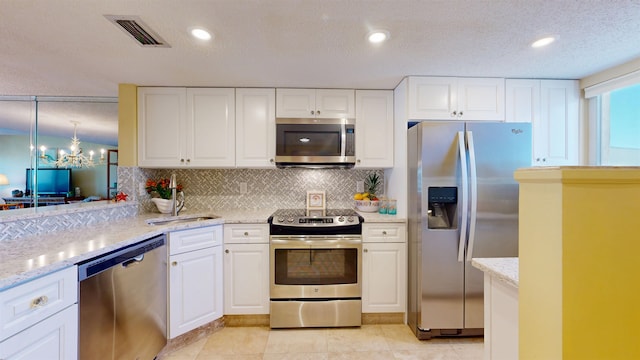 kitchen featuring appliances with stainless steel finishes, visible vents, decorative backsplash, and white cabinetry