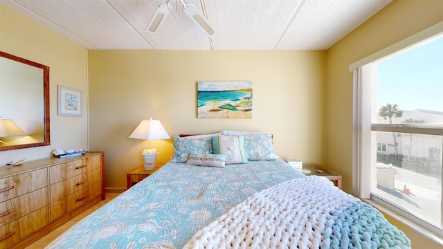 bedroom featuring access to exterior, a textured ceiling, and a ceiling fan