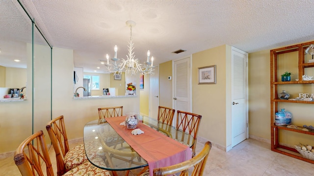 dining room featuring a chandelier, visible vents, a textured ceiling, and baseboards