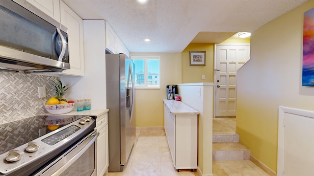 kitchen featuring appliances with stainless steel finishes, white cabinets, backsplash, and a textured ceiling