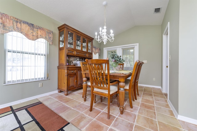 tiled dining room with lofted ceiling, a wealth of natural light, an inviting chandelier, and a textured ceiling