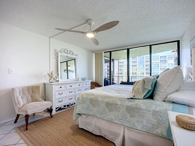 tiled bedroom featuring floor to ceiling windows, ceiling fan, and a textured ceiling