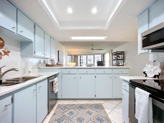 kitchen with sink, decorative backsplash, a textured ceiling, a tray ceiling, and stainless steel appliances