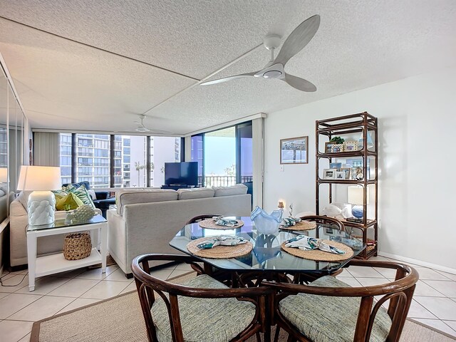 dining room featuring ceiling fan, light tile patterned flooring, a textured ceiling, and a wall of windows