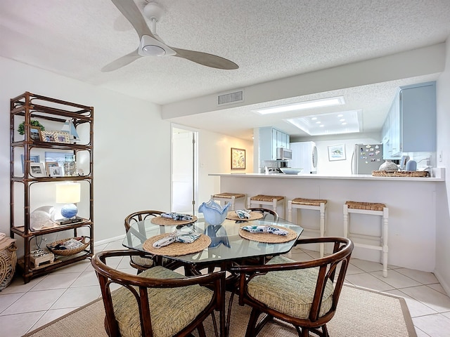 dining room featuring ceiling fan, light tile patterned floors, and a textured ceiling