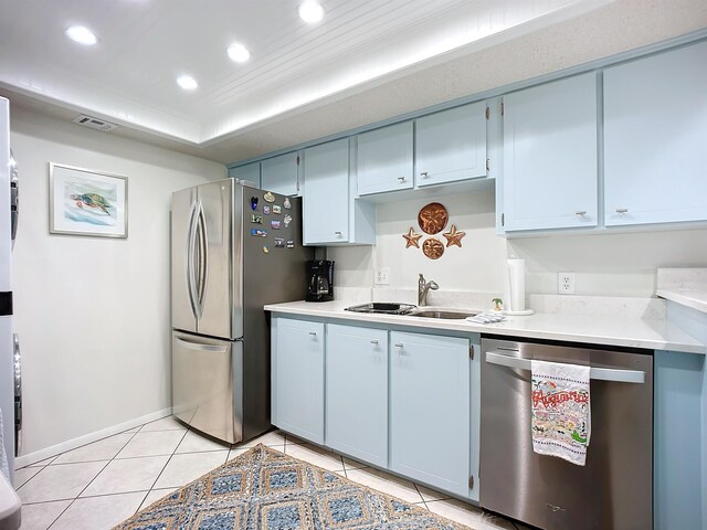 kitchen with light tile patterned flooring, appliances with stainless steel finishes, blue cabinets, and sink