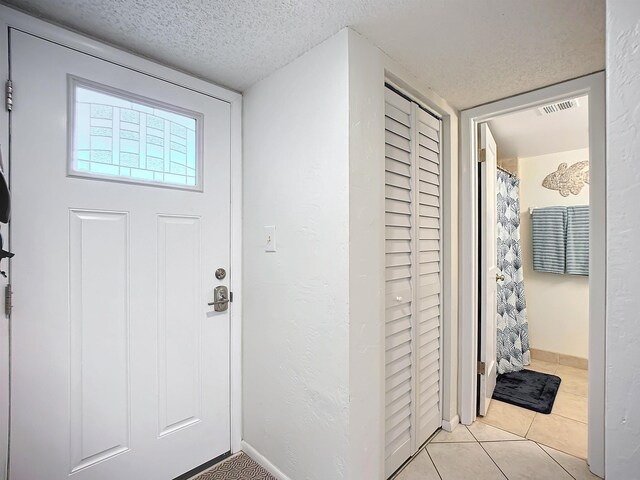 tiled foyer entrance featuring a textured ceiling