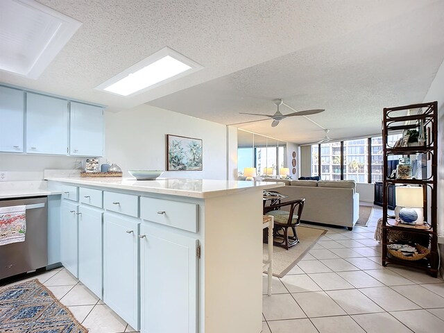 kitchen featuring light tile patterned floors, stainless steel dishwasher, kitchen peninsula, a textured ceiling, and white cabinets